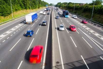 Looking down from above onto the busy carriageways of a motorway or highway that is full of speeding cars and trucks. Refresher Driving Lessons Belfast